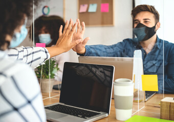 Young people in co-working creative space wearing surgical mask protection and keeping social distance to avoid corona virus spread - Health care and business technology concept
