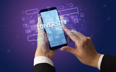 Female hand typing on smartphone with DIVERSITY inscription, social media concept