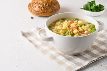Homemade soup with ditalini pasta, peas, ham on white table. Close up. Tasty dinner. Copy space.