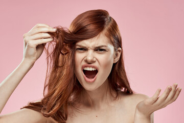 woman holding hair with hand problems hairstyle care emotions bare shoulders pink background