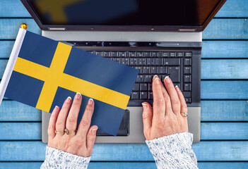 woman hands and flag of Sweden on computer, laptop keyboard 