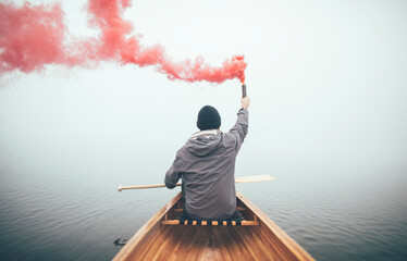 Canoeist using smoke bomb to signal his position on the foggy lake	