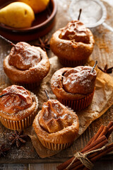 Homemade pear muffins with cinnamon sprinkled with powdered sugar on a wooden board, top view