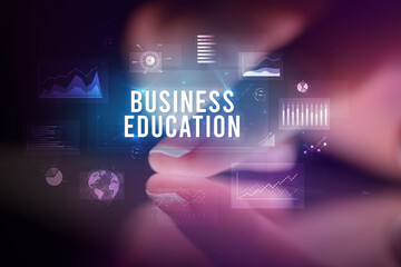 Finger touching tablet with charts and BUSINESS EDUCATION inscription, business concept