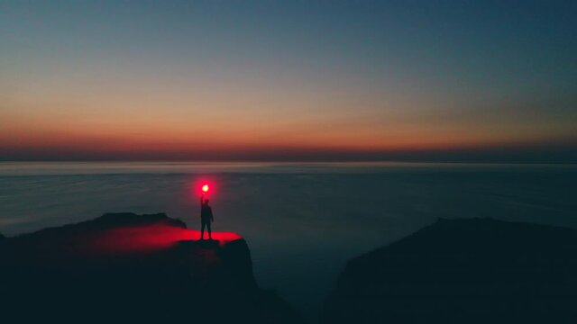 The male with burning firework stick is standing on the sunrise background