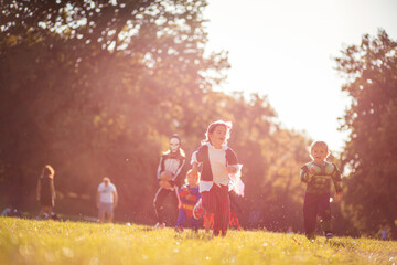 Obraz na płótnie Canvas Group of children in Halloween suits run through the park.