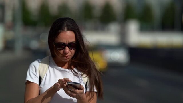 female tourist is orienting in new city by map in smartphone, using navigator at mobile phone