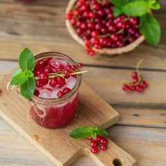 Glass jar of red currant soda drink on a wooden table. Summer healthy detox lemonade, cocktail or another drink background. Low alcohol, nonalcoholic drinks, vegetarian or healthy diet concept.