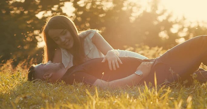 Couple lovers relaxing, hugging and kissing in the park at sunset. Love, youth, happiness concept. Health care, authenticity, sense of balance and calmness. 4K slow motion