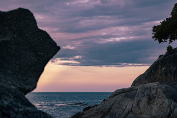 Spectacular colorful dramatic cloudy sky over sea and rocky beach at sunset 