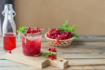 Glass jar of red currant soda drink on a wooden table. Summer healthy detox lemonade, cocktail or another drink background. Low alcohol, nonalcoholic drinks, vegetarian or healthy diet concept.