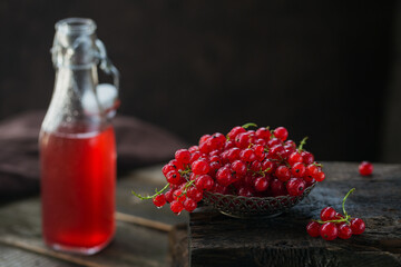 Heap of fresh red currant with water drops in a metal bowl on old dark wooden background. Healthy...