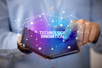 Businessman holding a foldable smartphone with TECHNOLOGY INNOVATION inscription, new technology concept