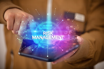 Businessman holding a foldable smartphone with RISK MANAGEMENT inscription, new business concept