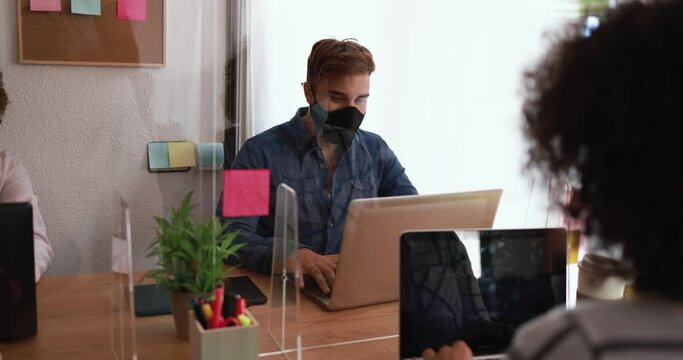 Young people working inside coworking office while wearing protective masks for coronavirus spread prevention