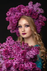 Beautiful teen girl on a dark background with beauty makeup in a smart dress with lilac