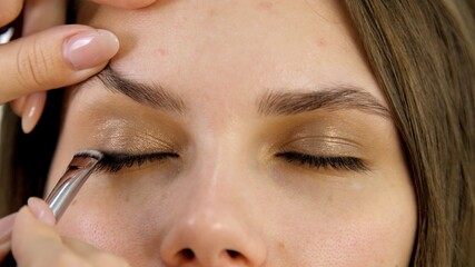 Attractive female close eyes of a brunette well-groomed woman. Master applies makeup with a special brush in a beauty salon. Beauty industry of cosmetics backstage of professional makeup. 