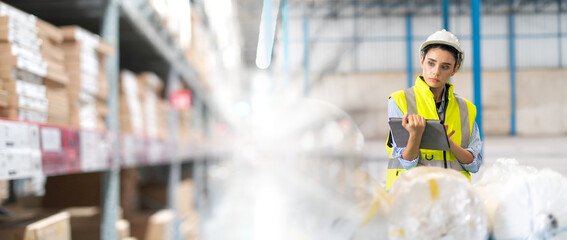 Female Inventory Manager working on digital tablet and checking quality of product at mask factory. Warehouse worker working at storage building.