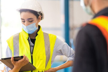 Female Inventory Manager working on digital tablet and checking quality of product at mask factory....