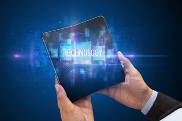 Businessman holding a foldable smartphone with TECHNOLOGY inscription, new technology concept