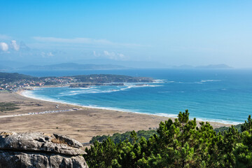 Aerial view of beaches and small villages along the Ria de Pontevedra in Spain, with the Cies Islands in the background.
