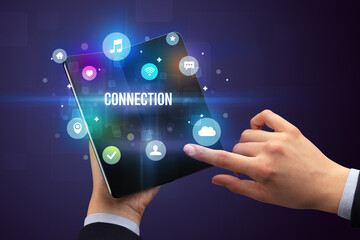 Businessman holding a foldable smartphone with CONNECTION inscription, social media concept