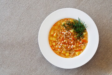 Soup with pickles, barley and vegetables on a linen tablecloth. Top view.