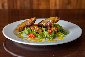 Chicken nuggets with tomatoes, herbs and sauce on a plate on a wooden background