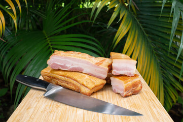 Smoked bacon. Cold cuts on a wooden board with palm background