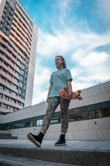 pretty young girl standing with penny board on street at sunny day