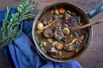 Traditional French boeuf bourguignon with vegetable offered as top view in a design bowl