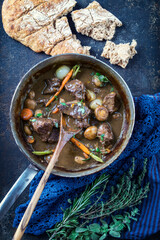 Traditional French boeuf bourguignon with vegetable and farmhouse bread offered as top view in a design bowl