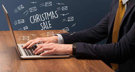 Businessman working on laptop with CHRISTMAS SALE inscription, online shopping concept