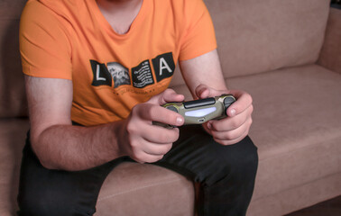 Male hands with game joystick, gamepad. The young guy is playing the console. Close up of man hands playing the video game at home. 