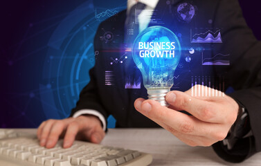 Fototapeta na wymiar Businessman holding lightbulb with BUSINESS GROWTH inscription, Business idea concept