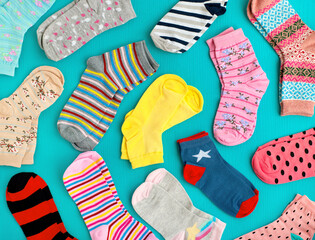 Multicolored socks for autumn and winter. Many different socks on a turquoise background. Clothes...