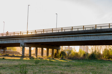 photography of people running and cycling over a bridge at sunset