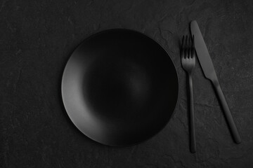 Black background with plate and cutlery, monochrome table setting - 385970254