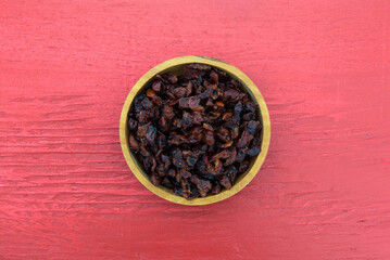 Top view of baking cranberries in a wood bowl on a red background.