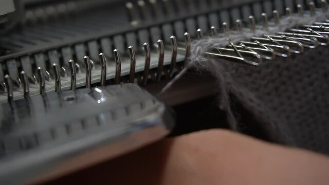 Female hands making textile on weaving machine at factory. Knitting machine Close up of weaving fabric on loom machine. Manufacturing knitted fabric on manual knitting equipment. Textile industry
