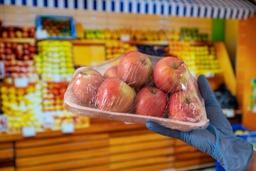 New normal after Covid-19 pandemic: A hand with blue protective gloves holds a plastic wrapped...