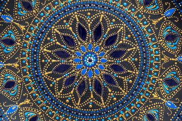 Decorative ceramic plate with black, blue and golden colors, painted plate on background , dot painting