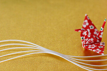 金色を背景に白い水引と赤い折鶴