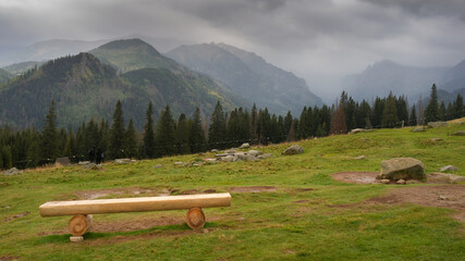 Empty wooden bench in tourist area with beauty Tatra Mountains view. Cloudy sky, rainy day. Rusinowa Polana, Poland, Europe.. © Fotema