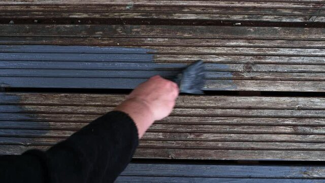Womens hands Painting faded old Garden Wooden Decking With Grey Paint