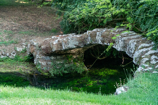 The river of the Garden of Ninfa, medieval stone bridge over the lake, relaxing view, Italy