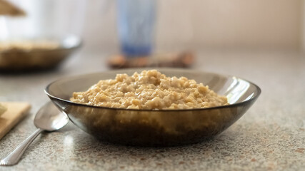 Glass bowl of oats porridge on the table. Healthy morning breakfast
