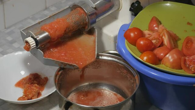 Making homemade fresh tomato juice with electric machine. Separation of bark and seeds from tomatoes juice.