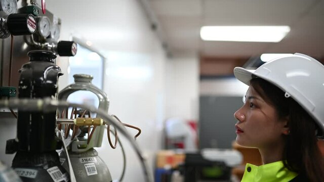 Asian engineer working at Operating hall,Thailand people wear helmet  work,He worked with diligence and patience,she checked the valve regulator at the hydrogen tank.