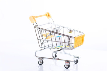 Yellow shopping cart with two Covid-19 vaccines on a white background, isolated, close up, macro photography